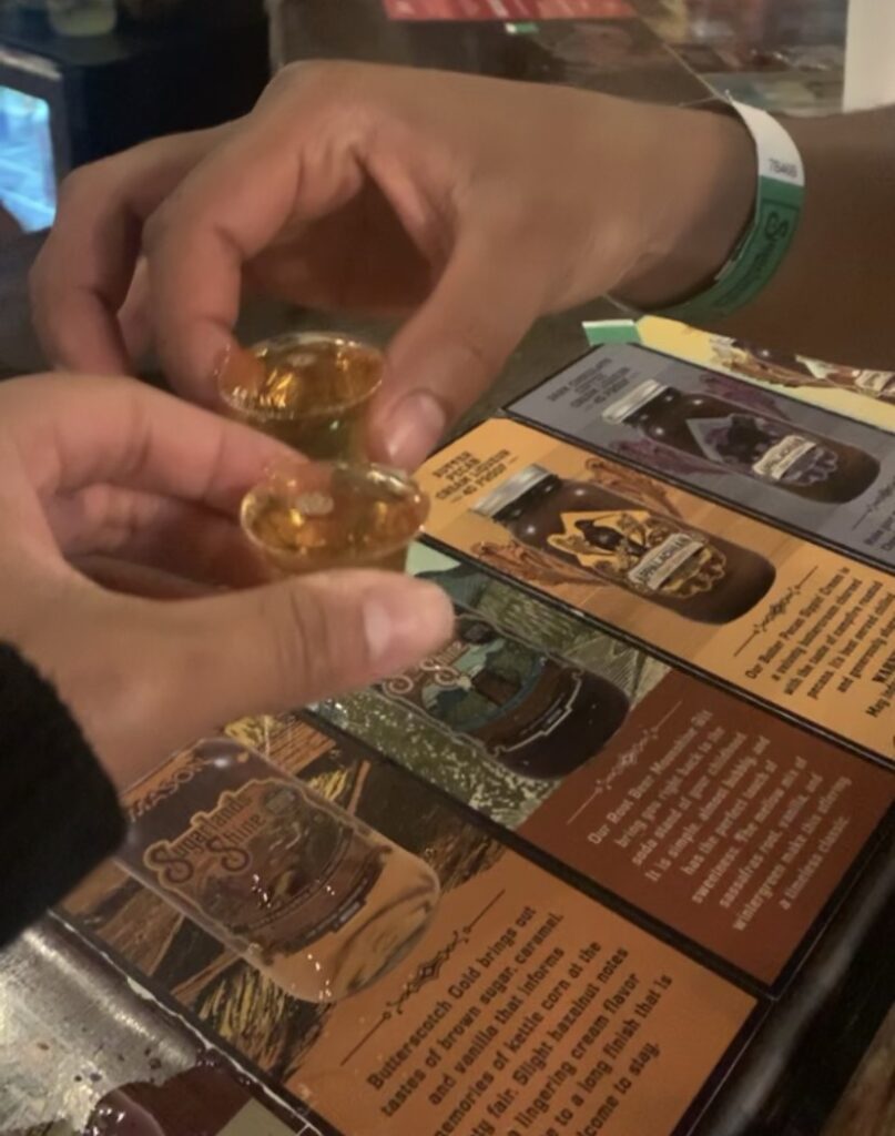 Two people holding mini-shots of moonshine